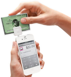 Hands running credit card through Square device on smartphone